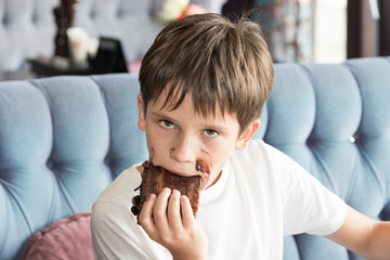 Fototapeta na wymiar The boy is eating a large piece of cake in his hands