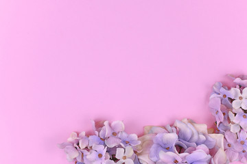 Background with artificial textile hydrangea flowers in lower right corner and blank pink copy space 