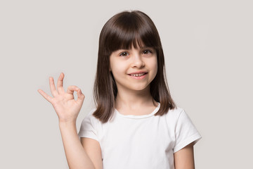 Attractive little 6 years old smiling cutie showing okay gesture.