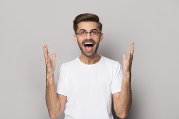 Fototapeta premium Cheerful young man in eyeglasses hearing unbelievable good news.