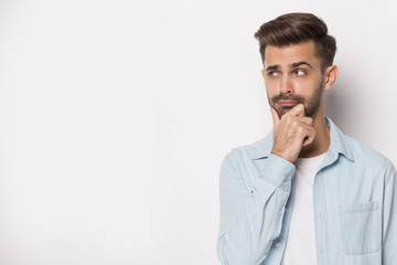 Pensive young guy looking aside at empty copy space.