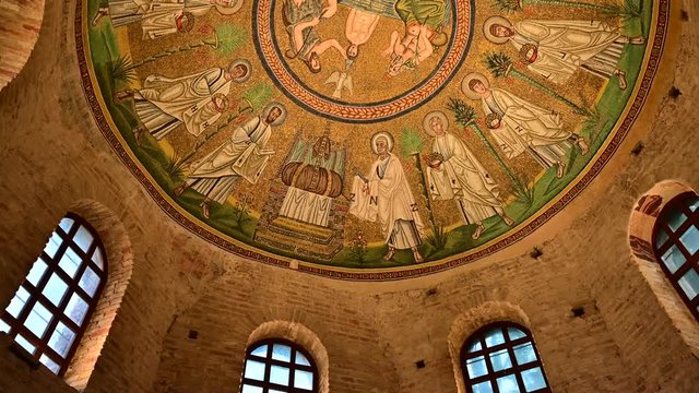 Ravenna, Italy, December 2019. Baptistery of the Aryans. Tilt movement footage towards the magnificent mosaics of the vault. From the red brick walls we move on to the colorful mosaic.