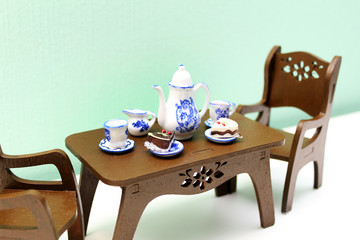  Toy brown wooden table with teapot, cups and saucers and two chairs