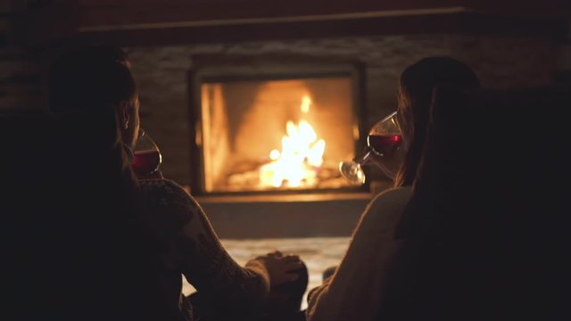 The young couple drinking wine near the fireplace