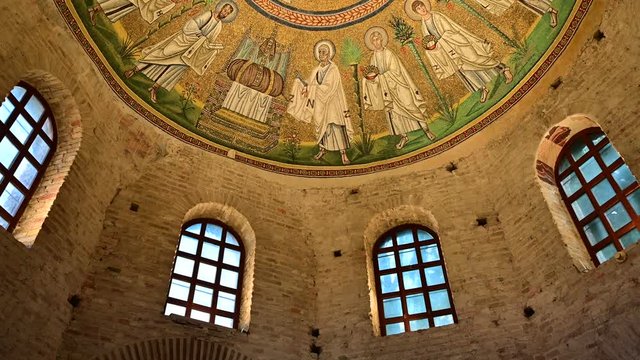 Ravenna, Italy, December 2019. Baptistery of the Aryans. Tilt movement footage towards the magnificent mosaics of the vault. From the red brick walls we move on to the colorful mosaic.