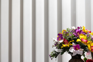 Bouquet of artificial flowers on a plastic curtain backdrop.