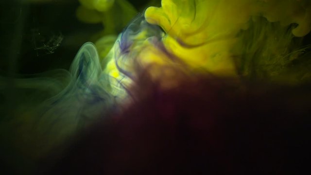 Real Shot Color Paint Drops In Water In Slow Motion. Ink Swirling. Color Ink Dropped In Water On Black Background. Cloud Of Silky Ink In Water Isolated.