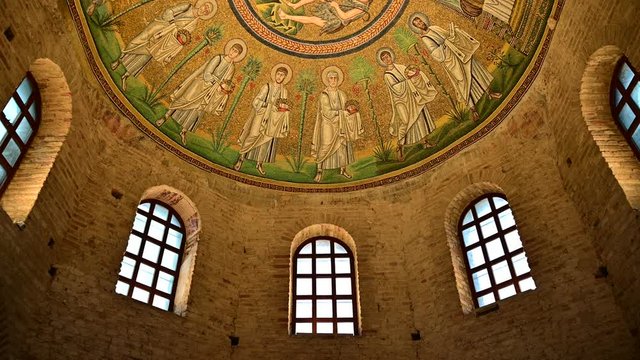 Ravenna, Italy, December 2019. Baptistery of the Aryans. Tilt movement footage towards the magnificent mosaics of the vault. From the red brick walls we move on to the colorful mosaic.