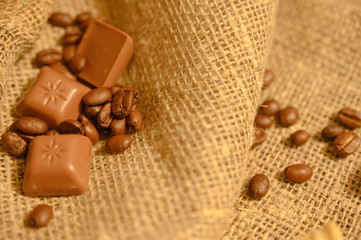 Chocolates and coffee beans on a background of rough homespun fabric. Close up.