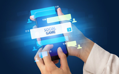 Female hand typing on smartphone with SOCIAL GAME inscription, social networking concept