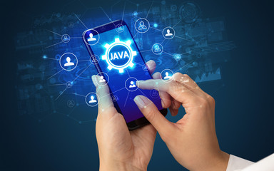 Female hand holding smartphone with JAVA abbreviation, modern technology concept