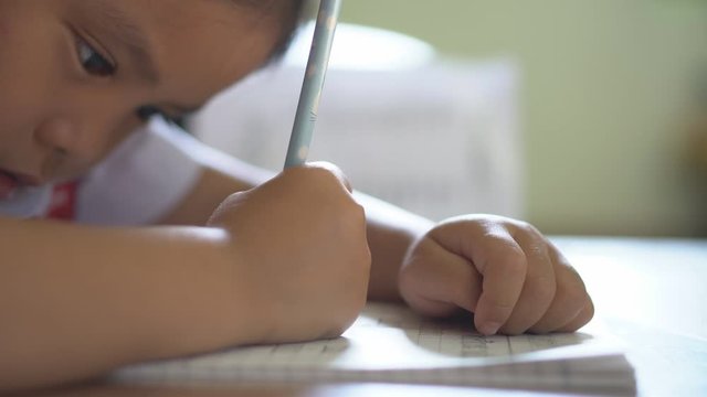 Asian child or kid girl learning and training for doing homework or coloring and drawing paint with write by pencil on paper notebook with at nursery or pre school and kindergarten on table 4K