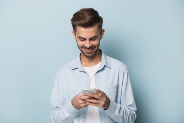 Happy millennial guy holding smartphone in hands.