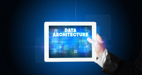 Young business person working on tablet and shows the inscription: DATA ARCHITECTURE