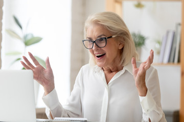 Middle-aged businesswoman feeling amazement received unbelievable online news