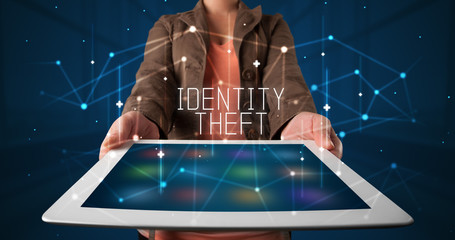Young business person working on tablet and shows the digital sign: IDENTITY THEFT