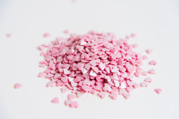A lot of small heart-shaped candies, piled up on a light background. Pink pills. The concept of sweet love. Concept. Lots of hearts.
