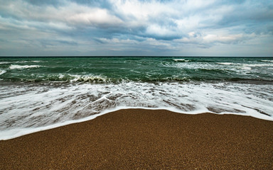 The Black sea waves and foam on beach sand