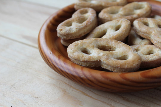 Close up, side on view of a wooden bowl filled with 'krakeling' a very popular sort of Dutch cookie. Wooden table background and copy space to the left.