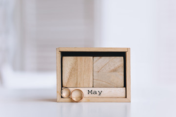 The month of May. Wedding rings close-up near the wooden casket of the calendar, as the scenery for shooting. Wedding accessories, details. Photography, concept.