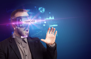 Businessman looking through Virtual Reality glasses with FRANCHISE inscription, new business concept