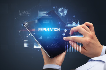 Businessman holding a foldable smartphone with REPUTATION inscription, successful business concept