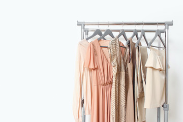 Spring summer beige women's clothing hanging on rail. Calm natural elegant colors. Minimal fashion clothes concept. Female dresses on hanger on white background. Blog, social media hero header