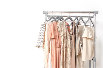 Spring summer beige women's clothing hanging on rail. Calm natural elegant colors. Minimal fashion clothes concept. Female dresses on hanger on white background. Blog, social media hero header