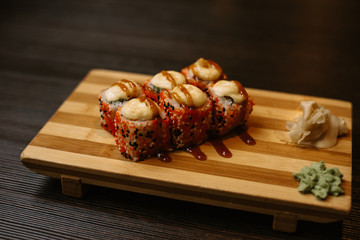 Set of hot baked rolls on a wooden tray with ginger and wasabi. Tasty sushi in a chinese restaurant