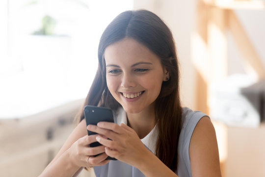 Attractive young woman smiling looking at smartphone screen