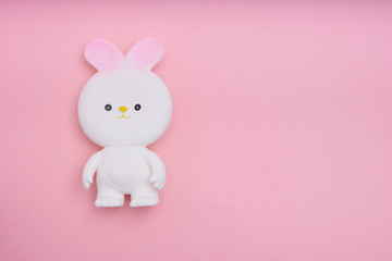 White easter bunny toy on pink background Top view