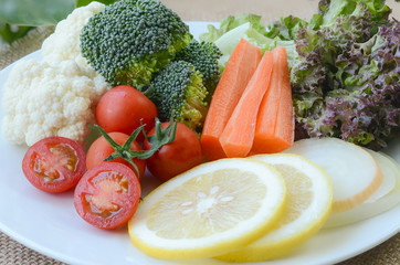fresh organic vegetables on white plate over fabric background