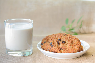 Chocolate chips cookies and a glass of milk on a fabric background.