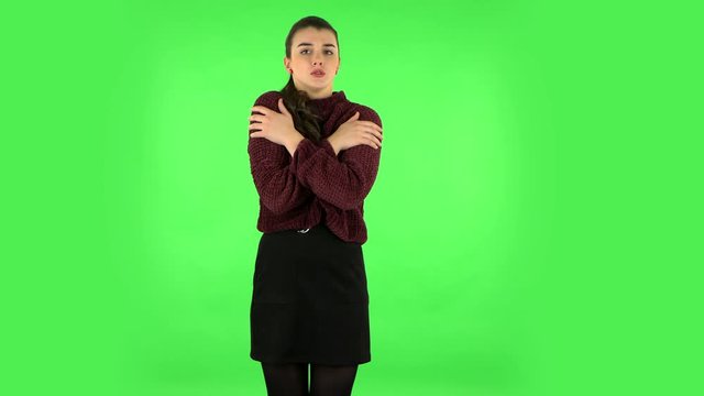 Beautiful sweet girl froze and trying to keep warm against green screen. Green screen