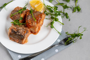 Cod fillet or other fish. Stewed in tomato and onion sauce. Peas are sprinkled with green leaves and microgreen from seedlings.