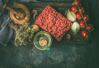 Raw minced meat with cooking ingredients for cooking on rustic background. Top view. Border