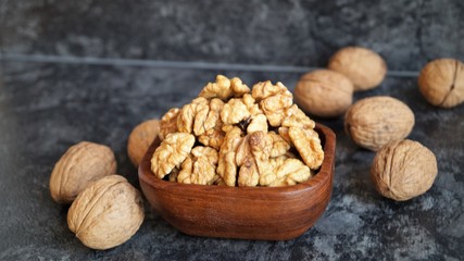 walnut kernels in a wooden dish on a black background