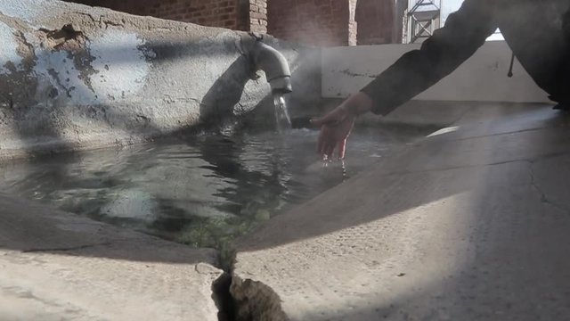 Mano  de mujer tocando  agua caliente en un lavadero antiguo de agua termal 