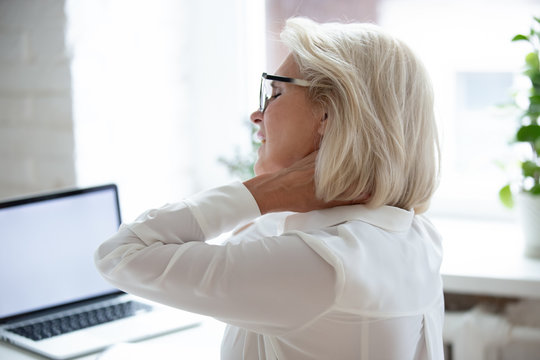 Rear closeup view middle-aged businesswoman suffers from neck pain