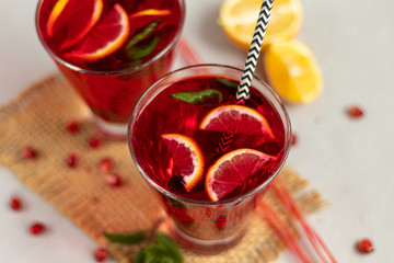Pomegranate juice in transparent glasses. On a light background under a stone. Trend 2020. Grains are scattered nearby.