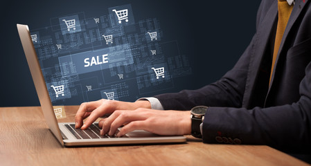 Naklejka na ściany i meble Businessman working on laptop with SALE inscription, online shopping concept