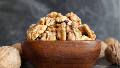 walnut kernels in a wooden dish on a black background