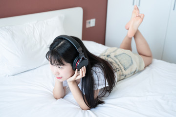 asian young woman listen to music headphone on bed