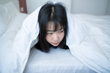 Obraz na płótnie Canvas sleepy asian woman rub her eye on bed warped pillow