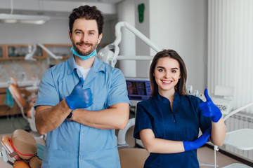 Obraz premium Portrait of smiling dentist standing with arms crossed with her colleague, showing okay sign.