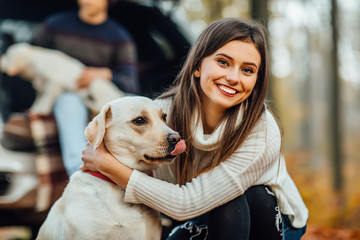 Beautiful young woman hugging her golden retriver labrador in the park.