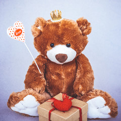 Valentines Day Teddy bear holding heart with text love and gift box. Retro romantic style. Creative greeting card.