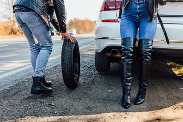 Obraz premium Zdjęcie z bliska, mężczyzna zmieniający oponę, z której przecieka jego samochód, zepsuł się w samochodzie kobiety.