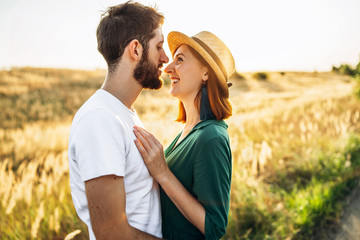 Happy young man and woman smiling and hugs outdoor at sunset. Concept of people, love and lifestyle