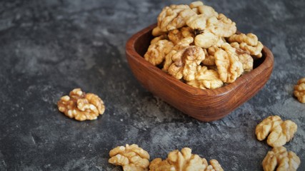 walnut kernels in a wooden dish on a black background